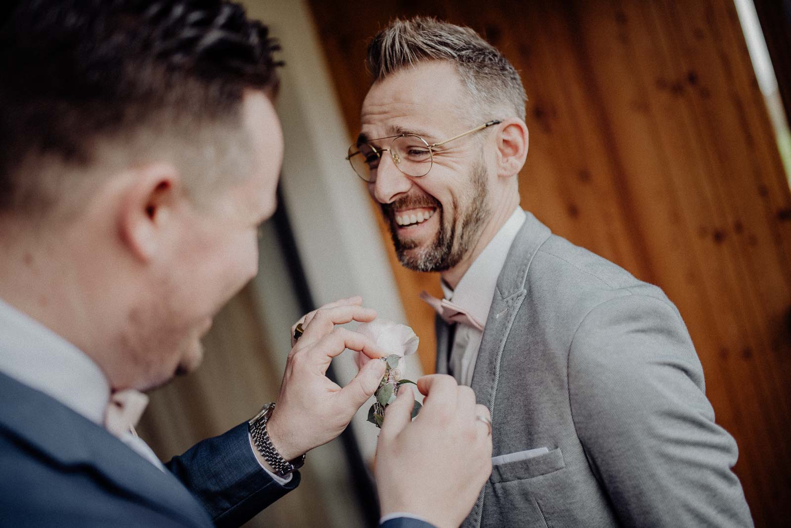 Trauzeuge hilft Bräutigam mit der Boutonniere