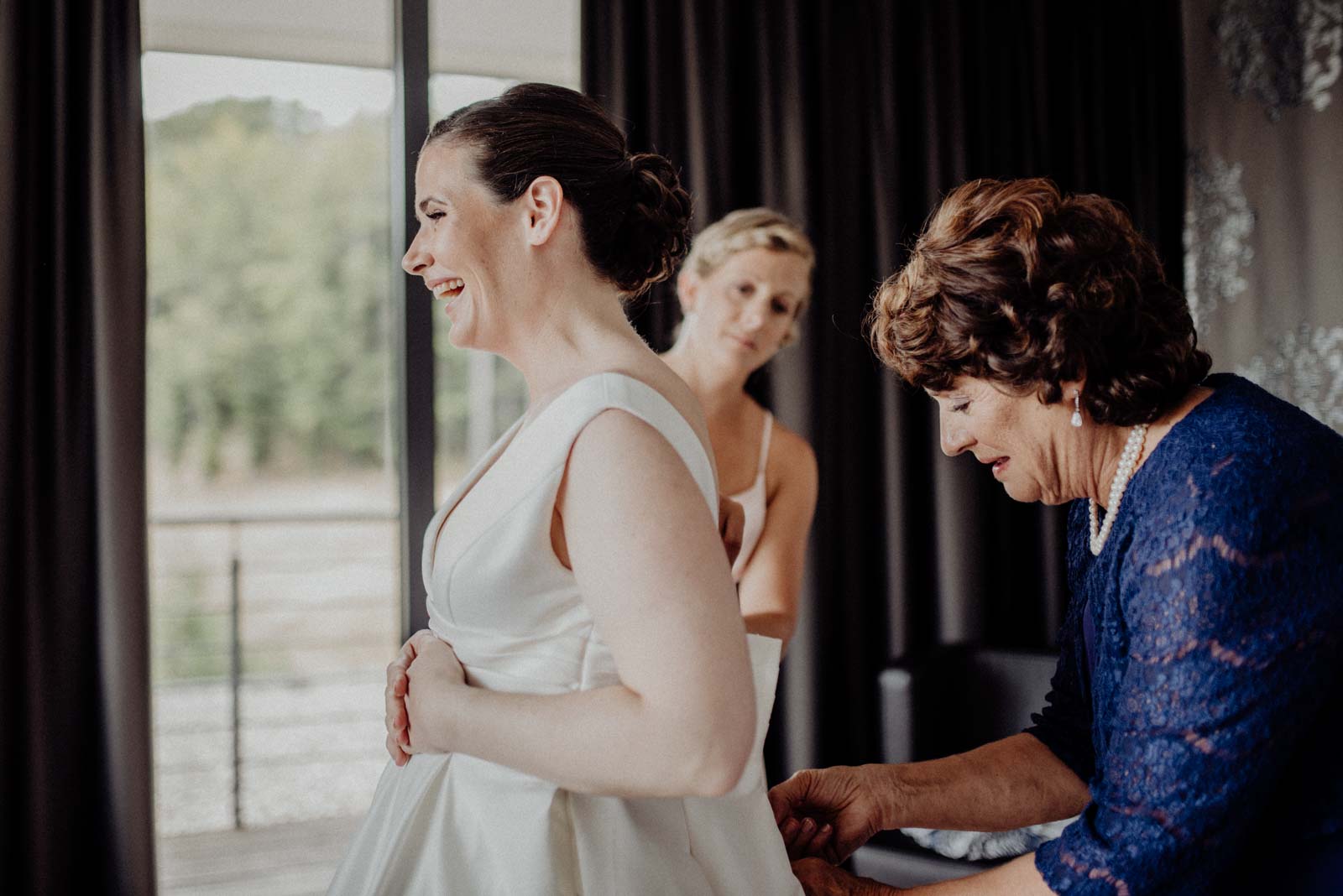 Brautmutter hilft ihrer Tochter ins Hochzeitskleid