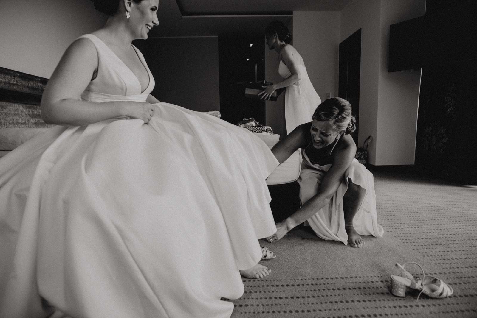 Brautjungfer hilft Braut ins Hochzeitskleid