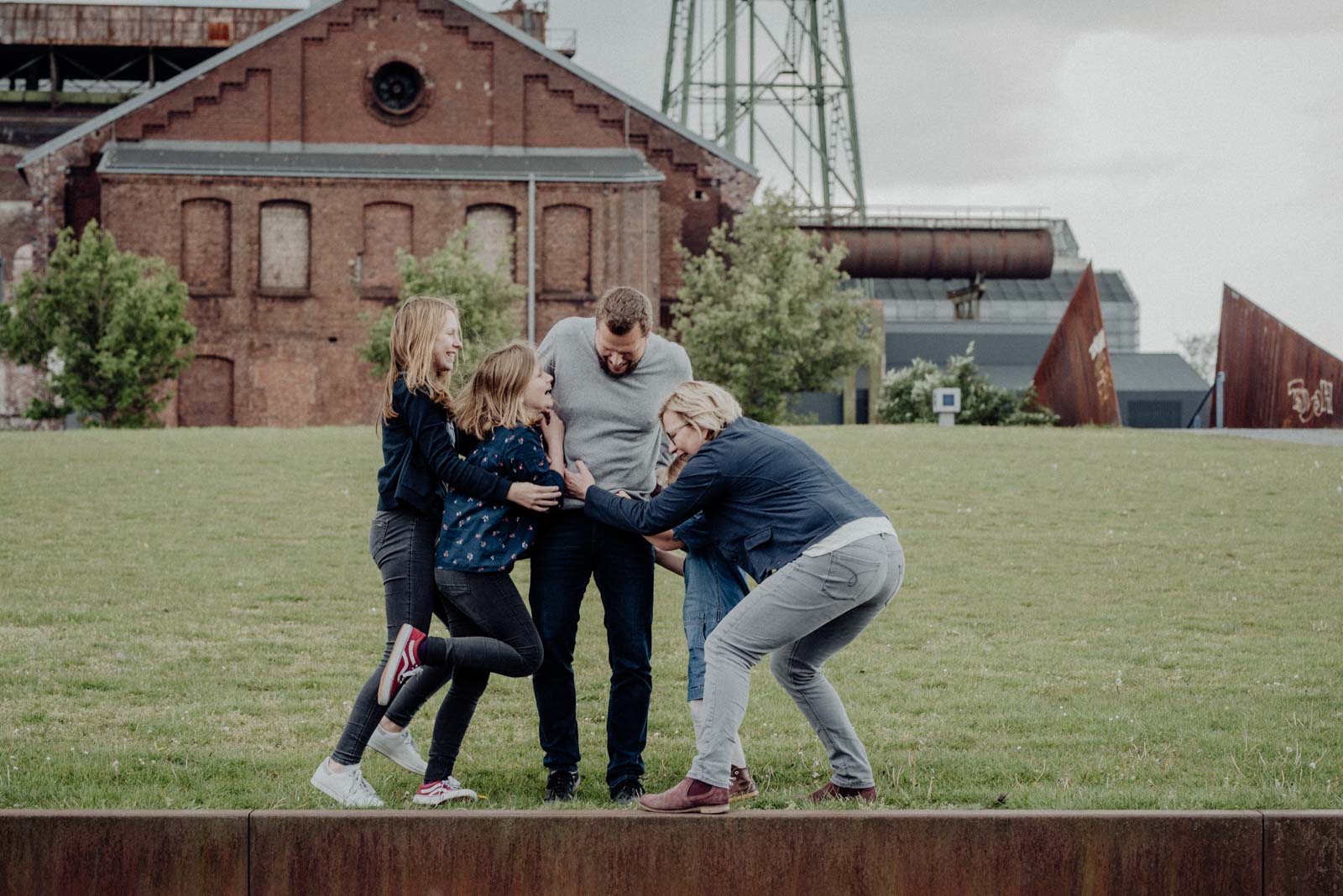 Alle kitzeln Papa beim Familienshooting.