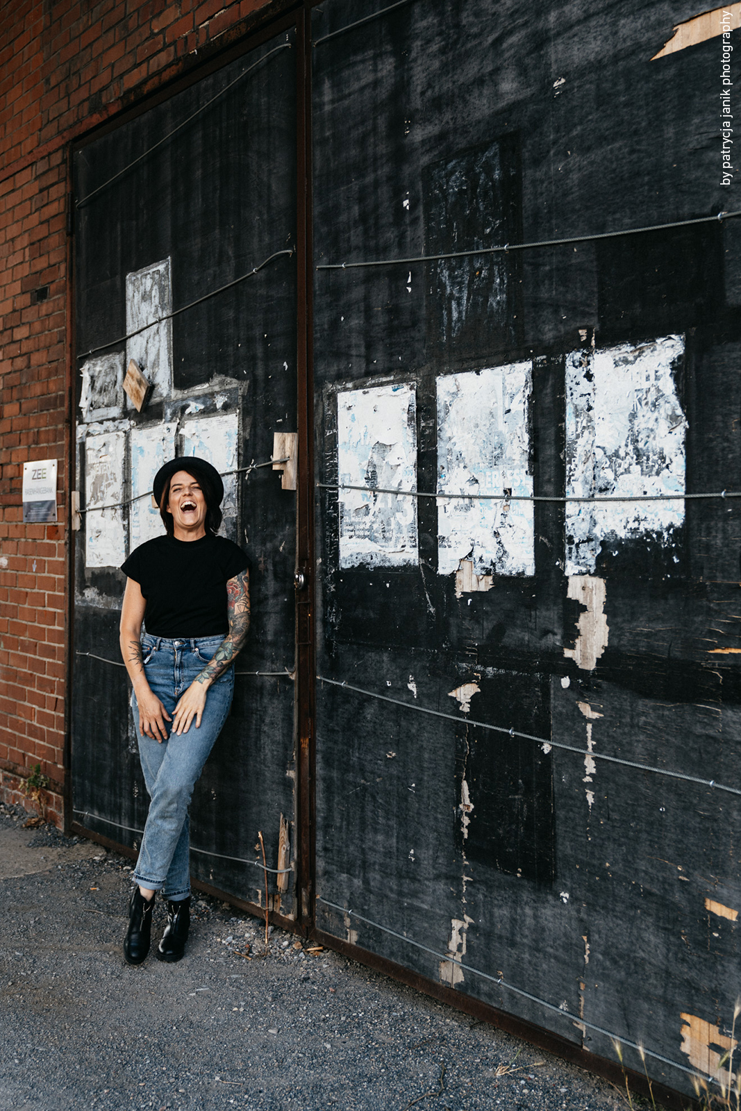 Fotografin mit Hut vor Plakatwand im Industriegebiet