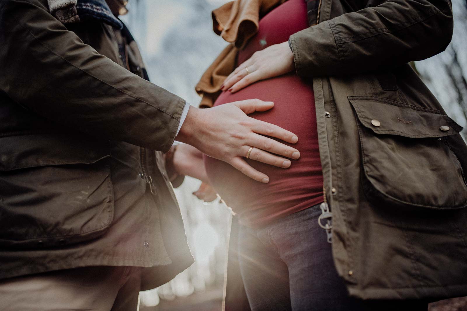 Werdender Papa hält den babybauch beim Paarshooting